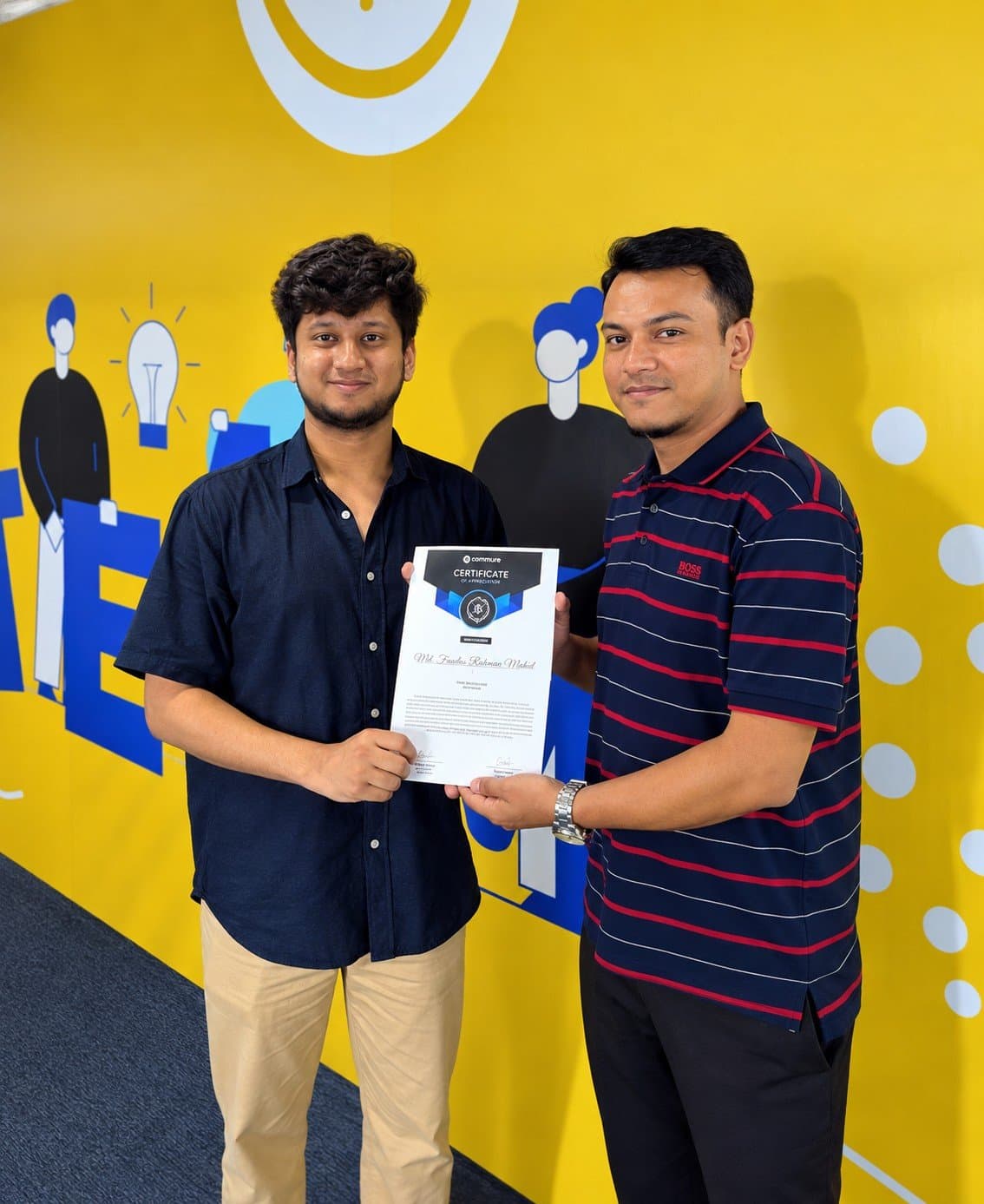 Receiving the Beast Award certificate from my team lead, in front of a yellow mural at the Commure office in Dhaka.