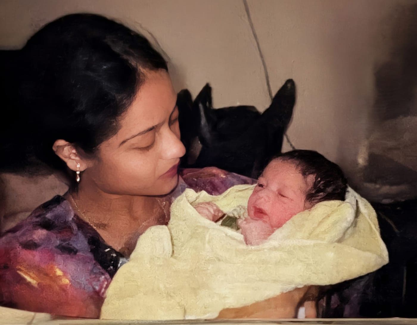 A newborn wrapped in a yellow blanket, held by my mother.