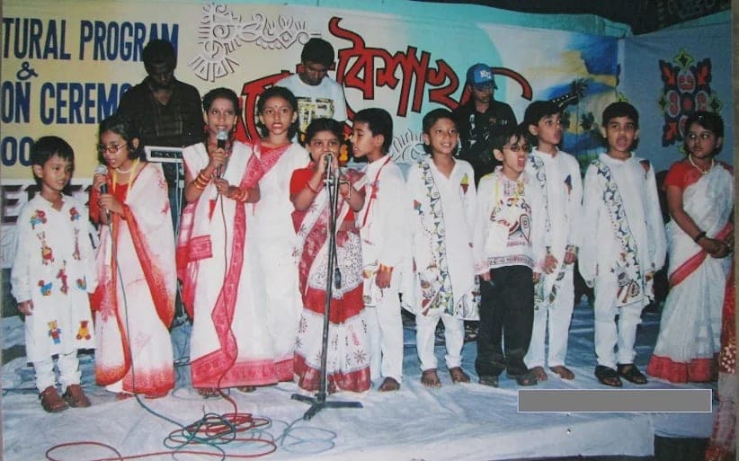 A row of small children singing on stage at a Pohela Boishakh programme.